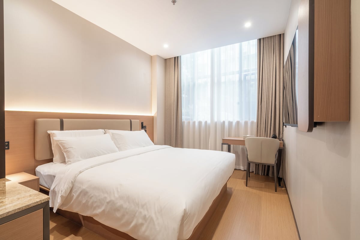 Una habitación de hotel moderna con una cama grande, un escritorio y una silla.