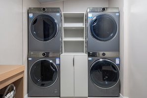 A laundry room with four Haier washing machines, a white cabinet, and a wooden shelf. - Yihe Hotel - Shanghai World Expo Museum (Shanghai)