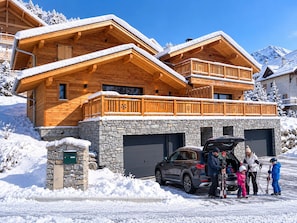 A wooden chalet with a stone foundation, a car with its trunk open, and people around it. - Chalet Cap'Sud - Two Bedroom Chalet, Sleeps 4 (Vaujany)