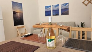 Un área de comedor con una mesa de madera, una botella de vino y copas de vino.