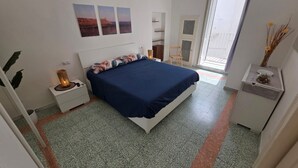 Un dormitorio con cama, mesita de noche, lámpara y vistas al exterior.