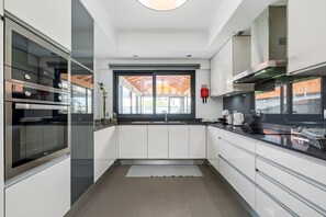 Una cocina moderna con electrodomésticos integrados, un ventanal con vistas y un extintor rojo.