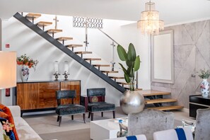 Un interior moderno con una escalera, zona de estar y elementos decorativos.