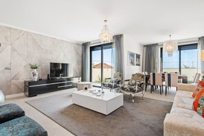 Un salon moderne doté d’un téléviseur à écran plat, d’une table basse et de différents espaces pour s’asseoir.
