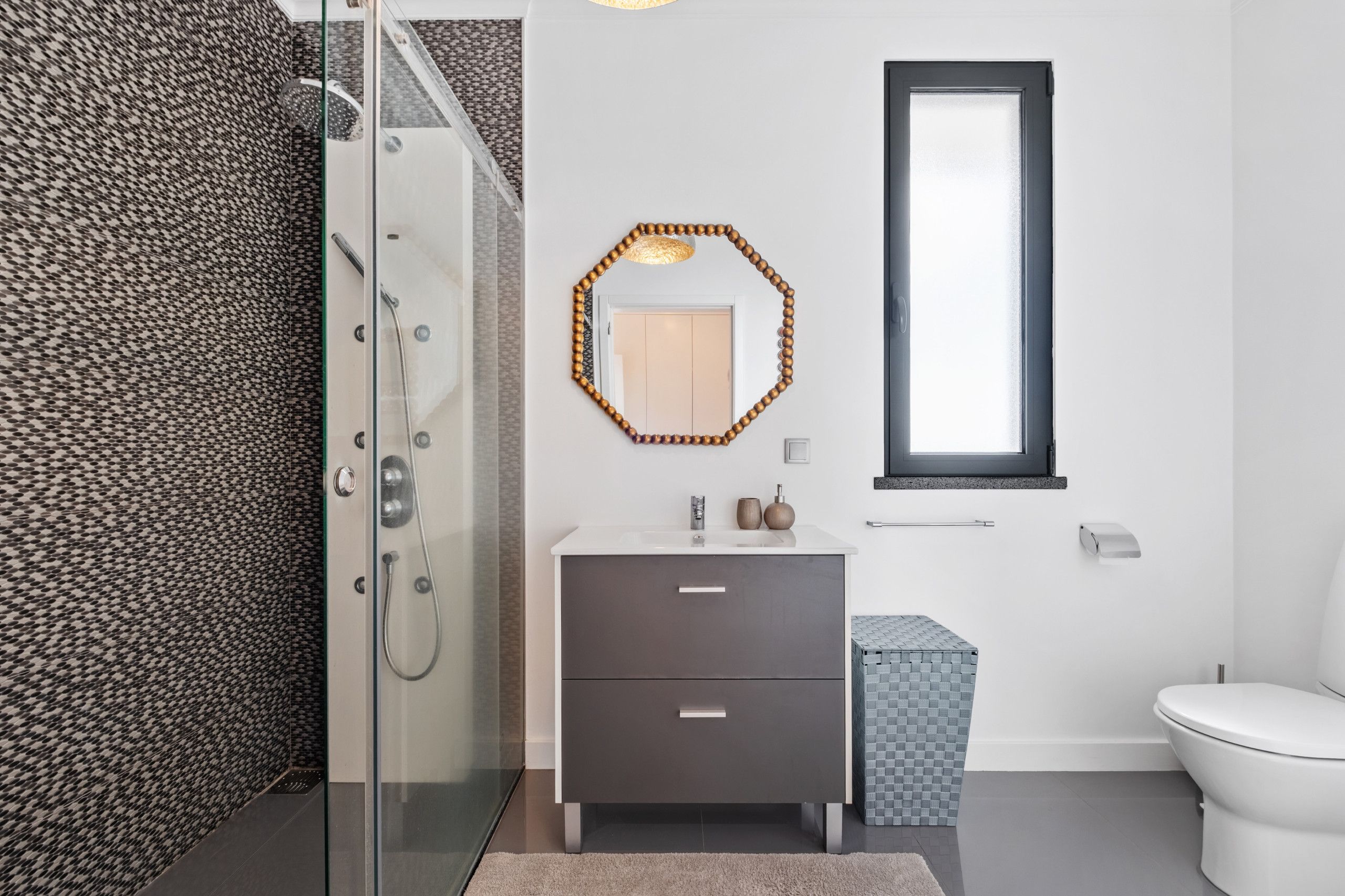 Un bagno moderno con doccia, lavandino e specchio, e un WC.