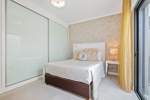 A modern bedroom with a large bed, a nightstand, a lamp, and a sliding glass door. - Villa Polaris by Homie (Funchal)