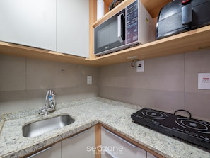 Eine Küche mit Granit-Arbeitsplatte, Edelstahl-Spüle, Mikrowelle und eingebautem Backofen.