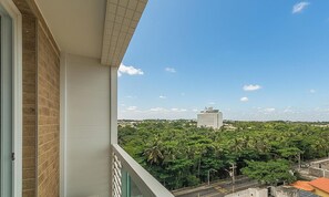 A balcony with a view of a dense green area and a distant building. - Studio w/ Sea View in Cond. w Pool Psp0605 (Salvador)