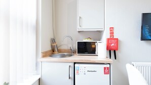 Eine kompakte Küchenzeile mit Spüle, Mikrowelle und kleinem Kühlschrank.