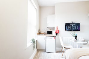 Ett litet, praktiskt kök med mikrovågsugn, ett litet kylskåp och en diskho.