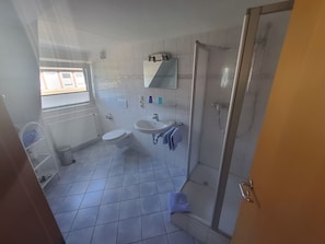 A bathroom with a toilet, sink, and shower. - Room 'Zum Elbblick - Doppelzimmer Nr.17' with Shared Terrace and Wi-Fi (Otterndorf)