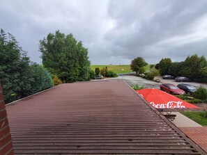 A parking area with cars and a Coca-Cola branded umbrella.