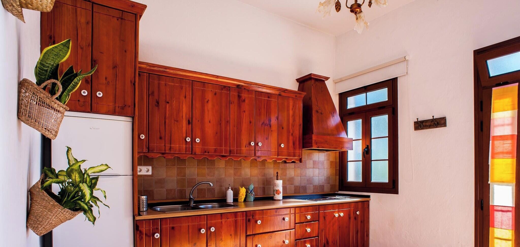 Una cocina con armarios de madera, un fregadero y un ventanal con paneles de vidrio esmerilado.