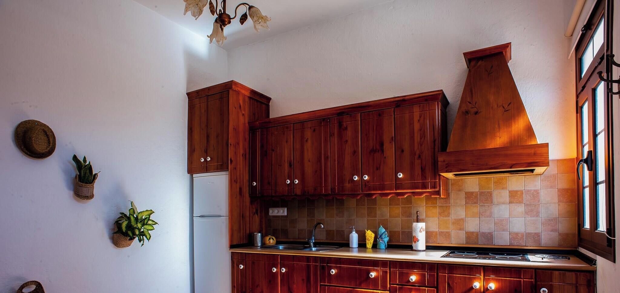 A kitchen with wooden cabinets, a stainless steel sink, and a tiled backsplash.