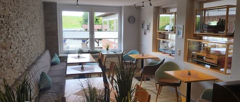 Ein modernes Interieur mit Backsteinwand, mehreren Sitzbereichen und Blick ins Freie.