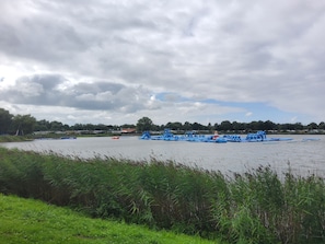 Une rivière parsemée de structures flottantes, une rive verdoyante et des maisons en arrière-plan.