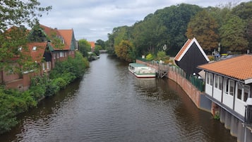 Ein schmaler Kanal, der von Gebäuden mit roten Ziegeldächern gesäumt wird, mit einem Boot, das an der rechten Seite liegt, und einer Brücke in der Ferne.
