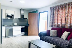 A modern kitchen with a microwave, oven, and a wooden door leading to a balcony. - Cave Stay near Mountain (Artenara)