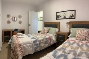 Ein Schlafzimmer mit zwei Betten, einem Nachttisch, einem Kleiderschrank und Wanddekorationen, darunter Uhren und ein gerahmtes Bild.