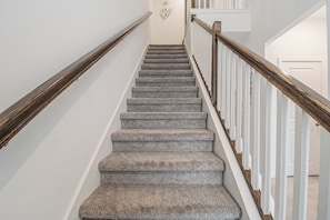 Ein Teppichbelag versehenes Treppenhaus mit Holzhandläufen und weißen Wänden.