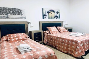 A hotel room with two beds, each with a headboard, bedside tables, and lamps. - Artenara Cave Stay with Solarium (Artenara)