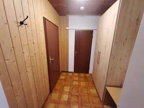 Un pasillo con paredes de madera y un suelo estampado, que conduce a dos puertas cerradas.