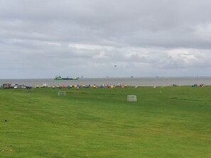 A grassy field with a green field, a goalpost, and a distant ship. - Room 'Zum Elbblick - Einzelzimmer Nr.20' with Sea View, Shared Terrace and Wi-Fi (Otterndorf)