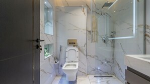 Un baño moderno con piso de mármol, cabina de ducha de vidrio y un inodoro con función bidé.