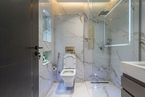 Ein modernes Badezimmer mit Marmorboden, einer Duschkabine aus Glas und einem WC mit Bidetfunktion.