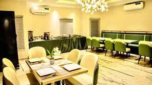 Un salón de conferencias con una larga mesa, sillas, una zona de buffet y un sofá verde.