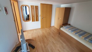 Een kamer met een bed, een kledingkast, een spiegel en een deur.