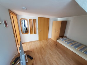 A room with a bed, wardrobe, mirror, and a door. - Room 'Zum Elbblick – Triple Room No. 16' with Shared Terrace and Wi-Fi (Otterndorf)