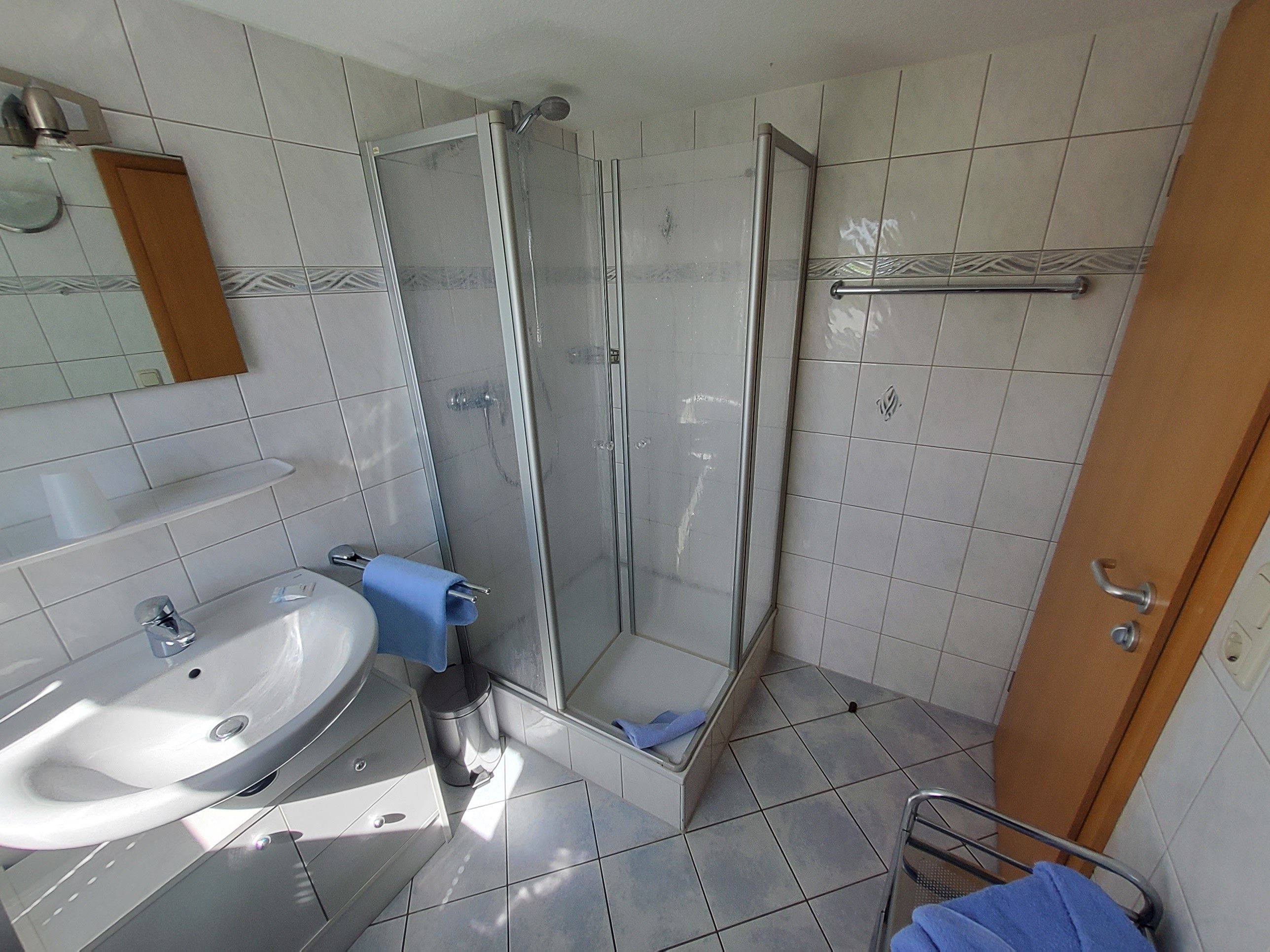 A bathroom with a shower, sink, and mirror.