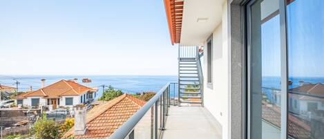 A balcony with a view of the sea and neighboring houses.
