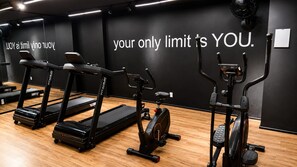 A gym with treadmills, an elliptical, and a stationary bike, with motivational wall text. - Premium Studio | Butantã Metro | USP (São Paulo)