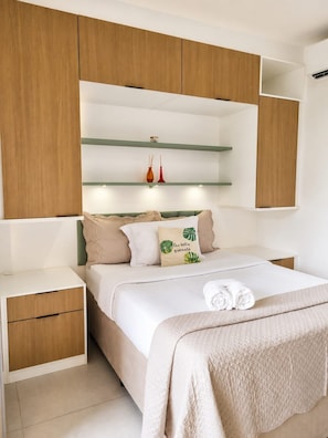 A bedroom with a bed, nightstands, and built-in wooden cabinets. - Premium Studio | Butantã Metro | USP (São Paulo)