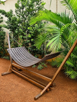 A hammock chair with a metal mesh seat and wooden frame, set on a wooden deck. - Premium Studio | Butantã Metro | USP (São Paulo)