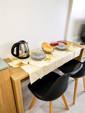 A dining table with a checkered tablecloth, a kettle, plates, a loaf of bread, and a red dessert. - Premium Studio | Butantã Metro | USP (São Paulo)