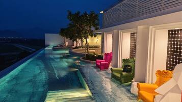A swimming pool with a tiled edge, surrounded by outdoor seating with cushions.