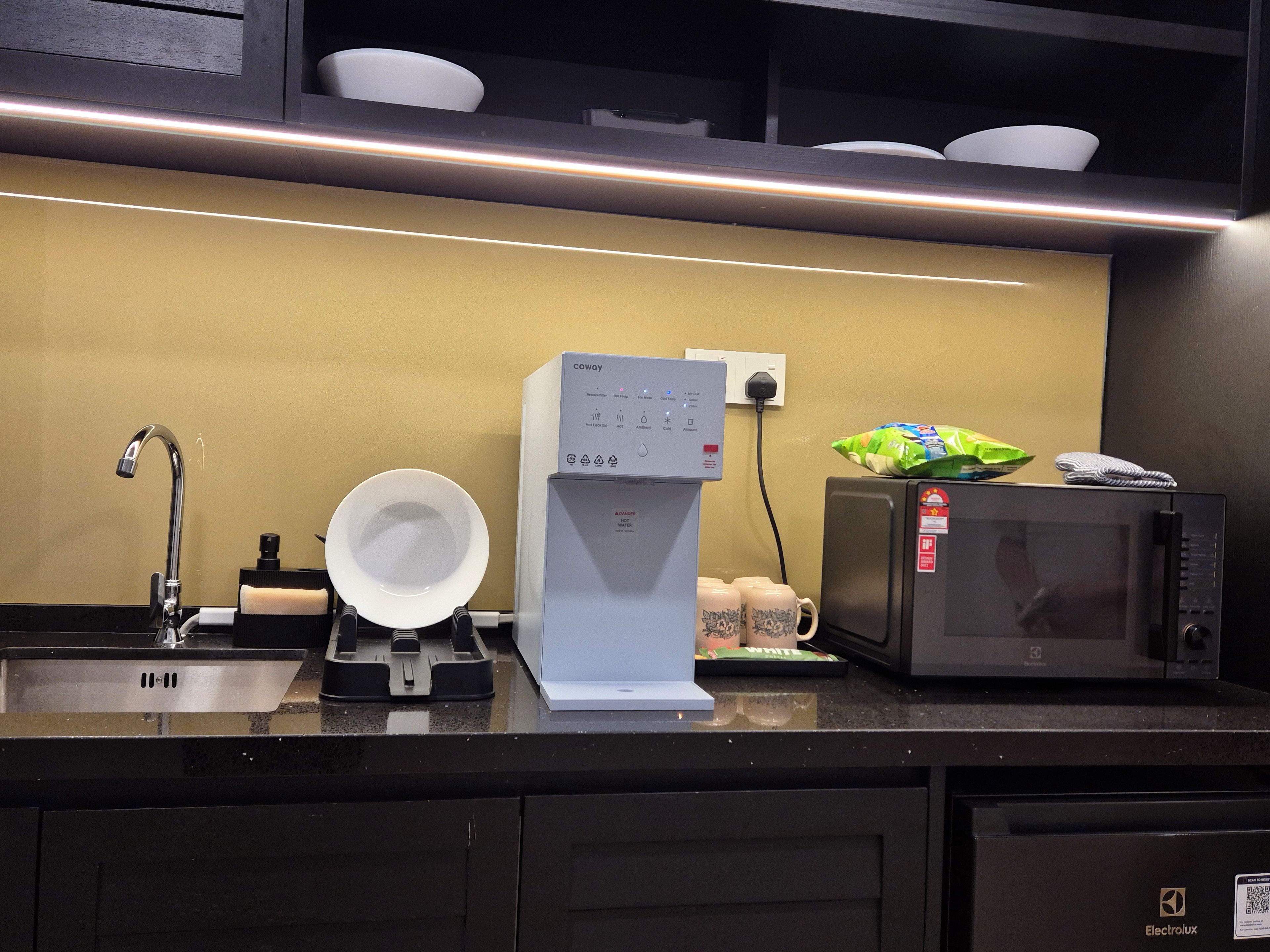 A kitchen with a coffee maker, microwave, and a sink.