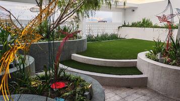 A landscaped garden with a lawn, curved stone planters, and decorative metal sculptures.
