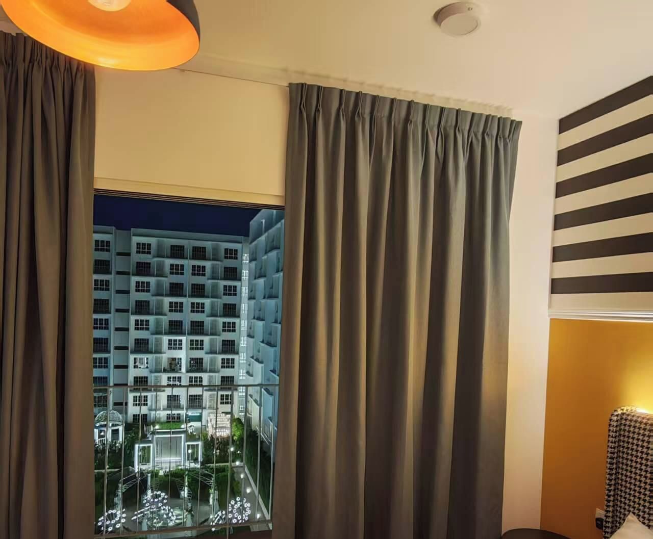 Camera d'albergo con vista su un complesso di edifici, tende e una parete a righe.
