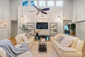 A spacious living room with a ceiling fan, a flat-screen TV, and a modern fireplace. - Spring Lakeview Retreat Near the Airport (Spring)