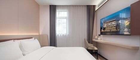 A hotel room with a large bed, a television mounted on the wall, and a window with curtains.