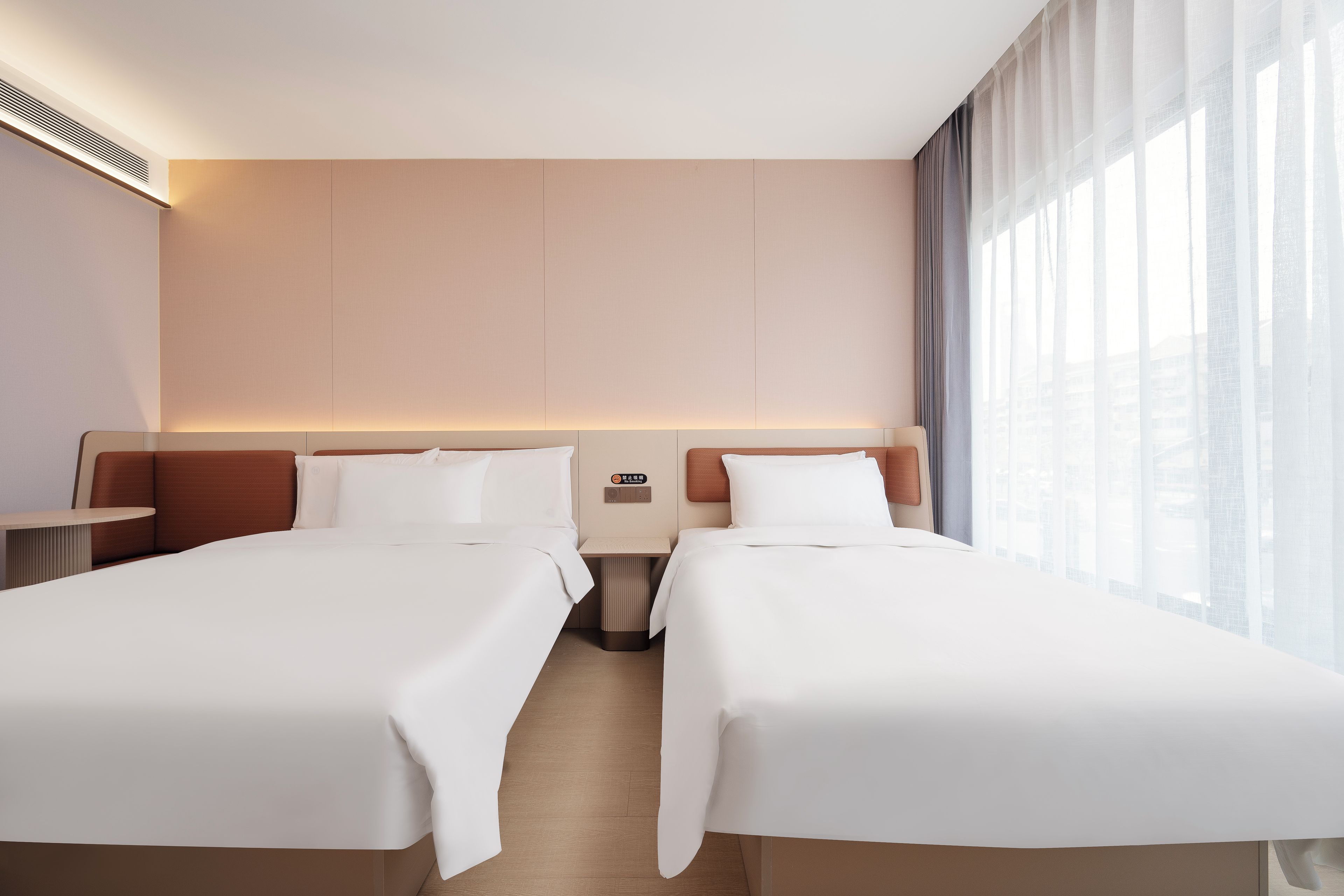 A hotel room with two beds, a bedside table, a nightstand, and a large window with curtains.
