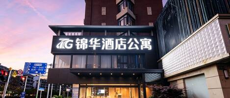 A hotel with a prominent sign, a modern facade, and a well-lit entrance.