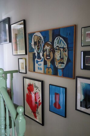 Eine Wand mit verschiedenen gerahmten Kunstwerken, darunter abstrakte und gegenständliche Gemälde.