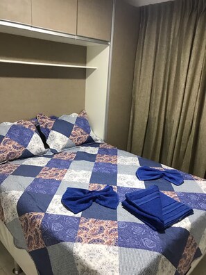 A neatly made bed with a patterned bedspread and two folded towels. - Apartment 101 · 101 Flat Good taste and quality (Belém)