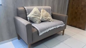 A grey armchair with a grey throw blanket and two beige pillows. - 102 Welcoming and cozy (Belém)