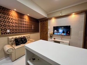 Un salon moderne avec un canapé, un téléviseur à écran plat fixé au mur et un meuble de rangement blanc.